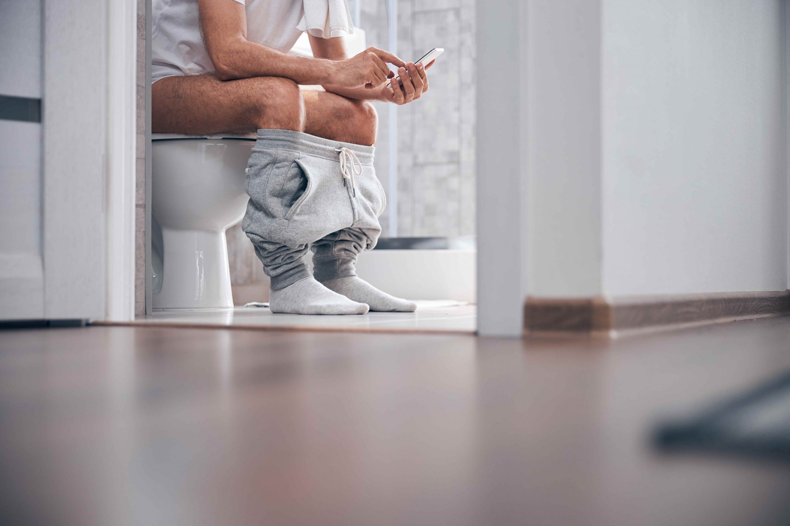 The picture shows a man sitting on the toilet